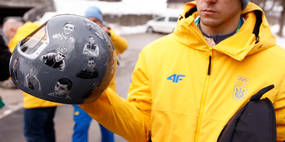 Diskvalificētais Ukrainas skeletonists Vladislavs Heraskevičs ar ķiveri bojāgājušo sportistu piemiņai.