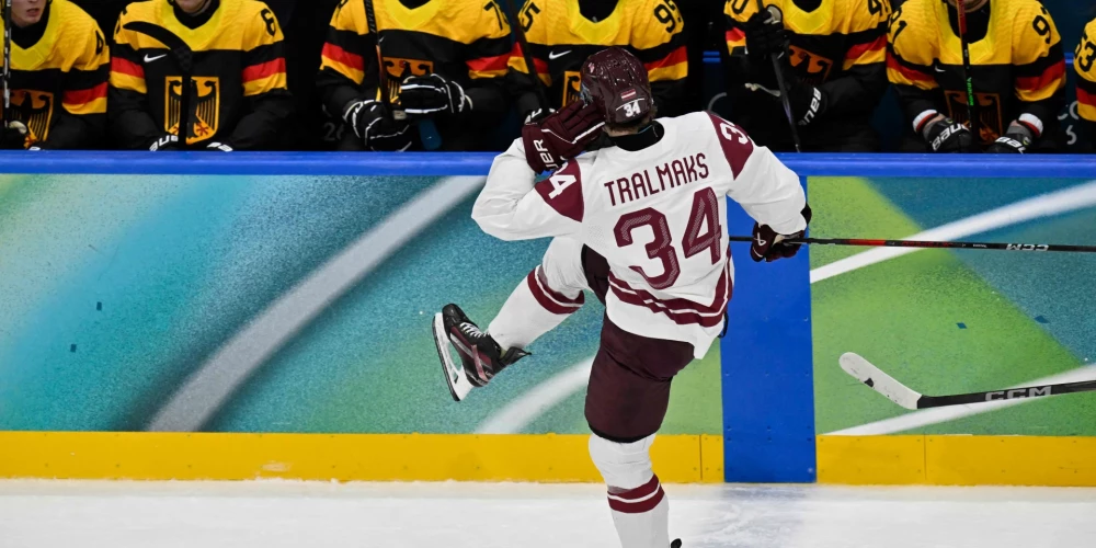 Eduards Tralmaks pēc vārtu guvuma slido gar saskābušo Vācijas izlases spēlētāju soliņu