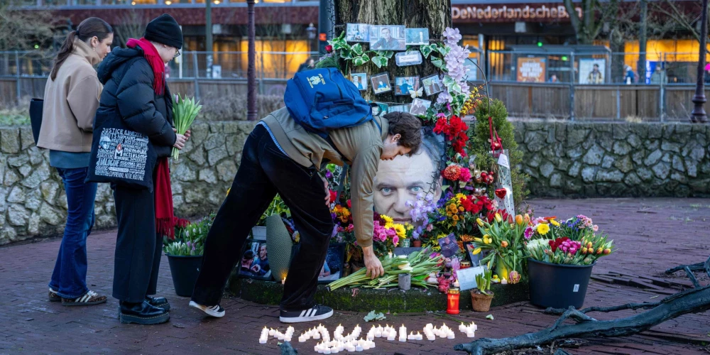 Сторонники покойного российского оппозиционного лидера Алексея Навального возлагают цветы к стихийному мемориалу, установленному на площади в Амстердаме, в день второй годовщины его смерти в заключении.