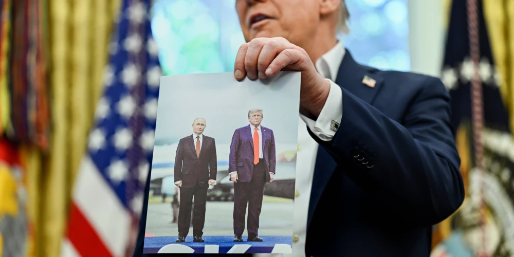 ASV prezidents Donalds Tramps tur rokās fotogrāfiju, kurā redzams viņš un Krievijas vadonis Vladimirs Putins.
