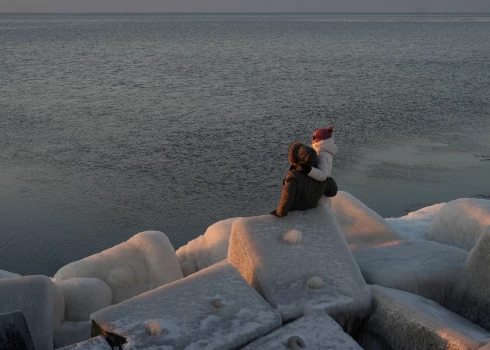 Cilvēki vēro saulrietu uz Mangaļsalas mola.