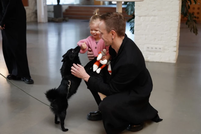 Elza tētim klēpī priecīga smaida par iepazīšanos ar jaunu suņuku, jo arī mājās viņa centīgi rūpējas par ģimenes četrkājainajiem draugiem.