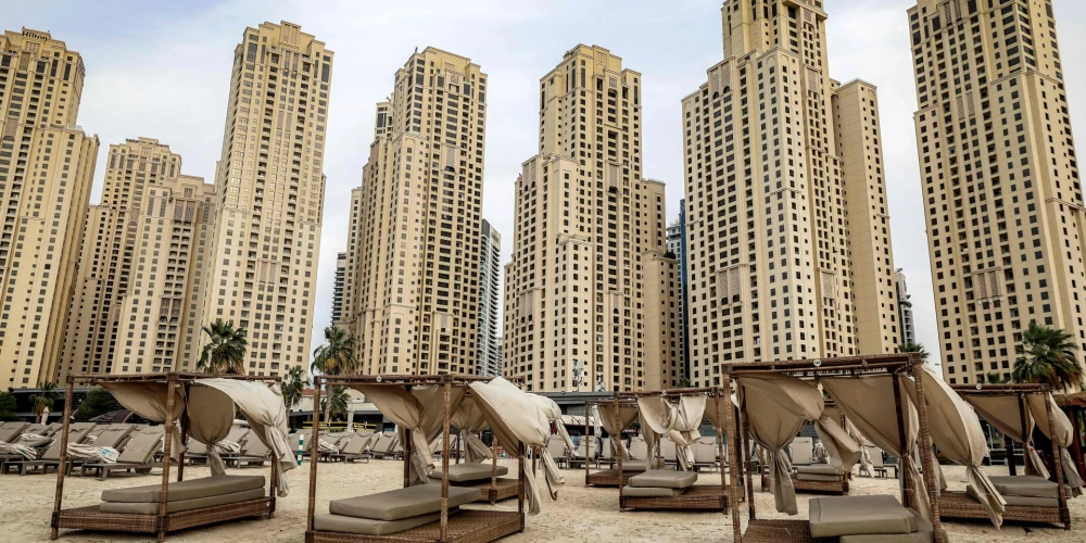 Пустые шезлонги стоят на пляже на фоне высотных зданий района Jumeirah Beach Residence в Дубае в середине марта 2026 года.