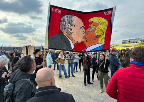 Protestētāji Prāgas ielās tur plakātu ar stilizētu Donalda Trampa un Vladimira Putina skūpstu.