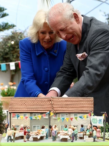 Karalis un karaliene smejoties ar zobenu greiza kūku, kas padevās nedaudz šķībā leņķī.
