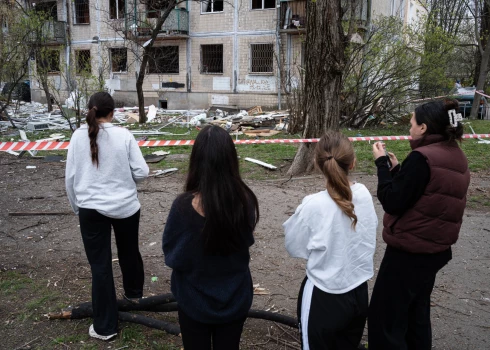 Kijivas meitenes skatās uz krievu dronu uzbrukumā 2026. gada 16. aprīlī sapostīto māju