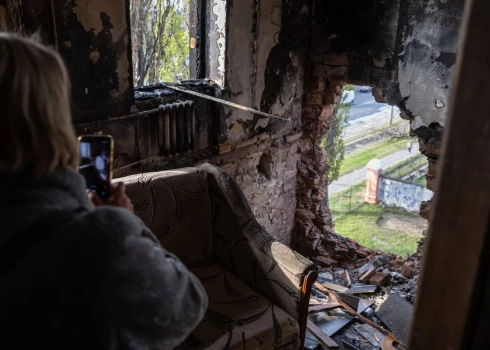 Женщина фотографирует поврежденную стену общежития после воздушной атаки в Одессе 30 апреля 2026 года, на фоне продолжающегося российского вторжения в Украину.