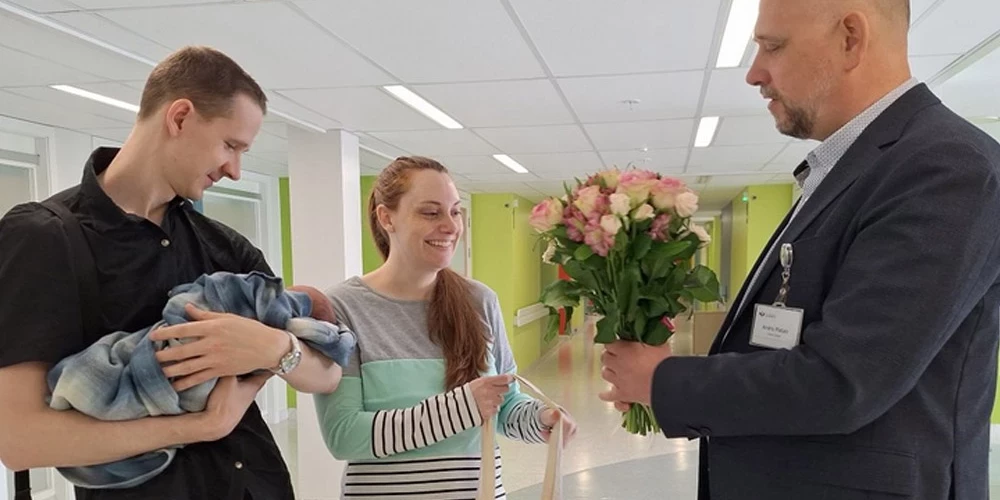 Lindsija Deivisone, Ilmārs Bērziņš un viņu meitiņa Jasmīne saņem apasveikumu no Liepājas Reģionālās slimnīcas valdes locekļa Andra Platā.