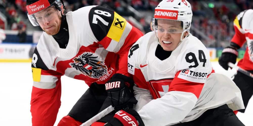 Austrijas hokejists Timo Nikls (pa kreisi) cīnās par ripu pret Šveices spēlētāju Atīlio Bisku.
