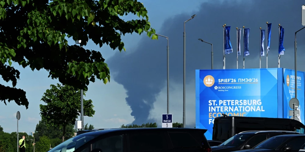 Cars are seen parked near banners with branding for the St. Petersburg International Economic Forum (SPIEF) at the forum's venue as black smoke rises in distance in Saint Petersburg on June 3, 2026. Ukrainian drones hit energy and military sites in Saint Petersburg early Wednesday morning as officials gathered for a flagship economic forum in the city, Russian and Ukrainian authorities said. Saint Petersburg Governor Alexander Beglov, said "several" infrastructure facilities were damaged, but no one was killed in the attack. (Photo by AFP)